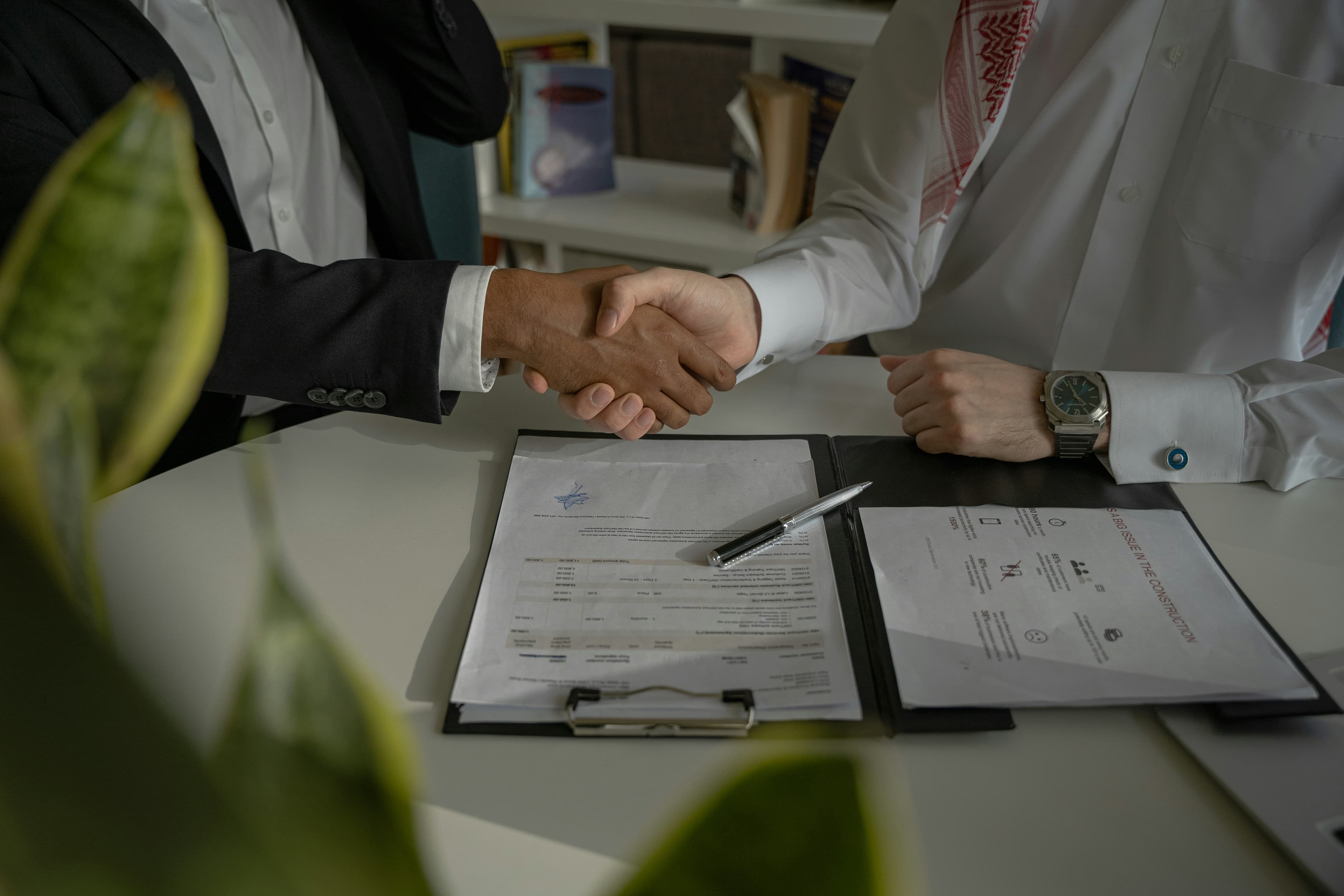 Dos personas dándose la mano sobre un documento.