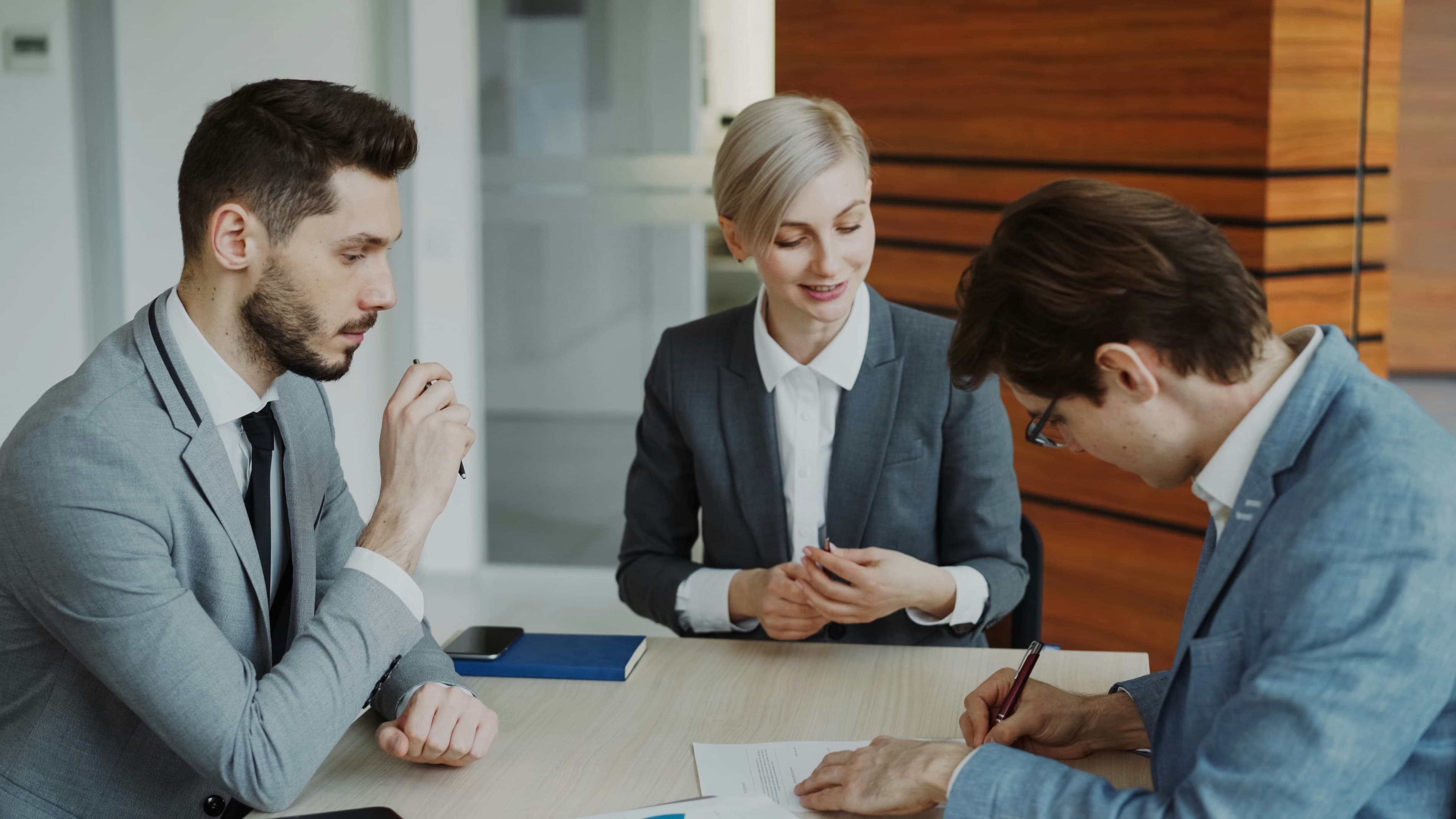 Personas firmando un contrato en una mesa.